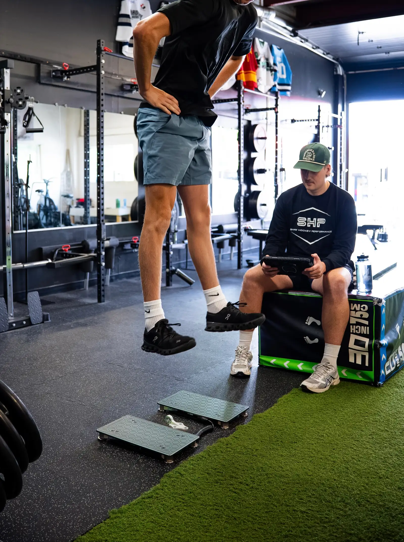 Athlete completing a countermovement jump on VALD ForceDecks with Coach Shaw reviewing metrics
